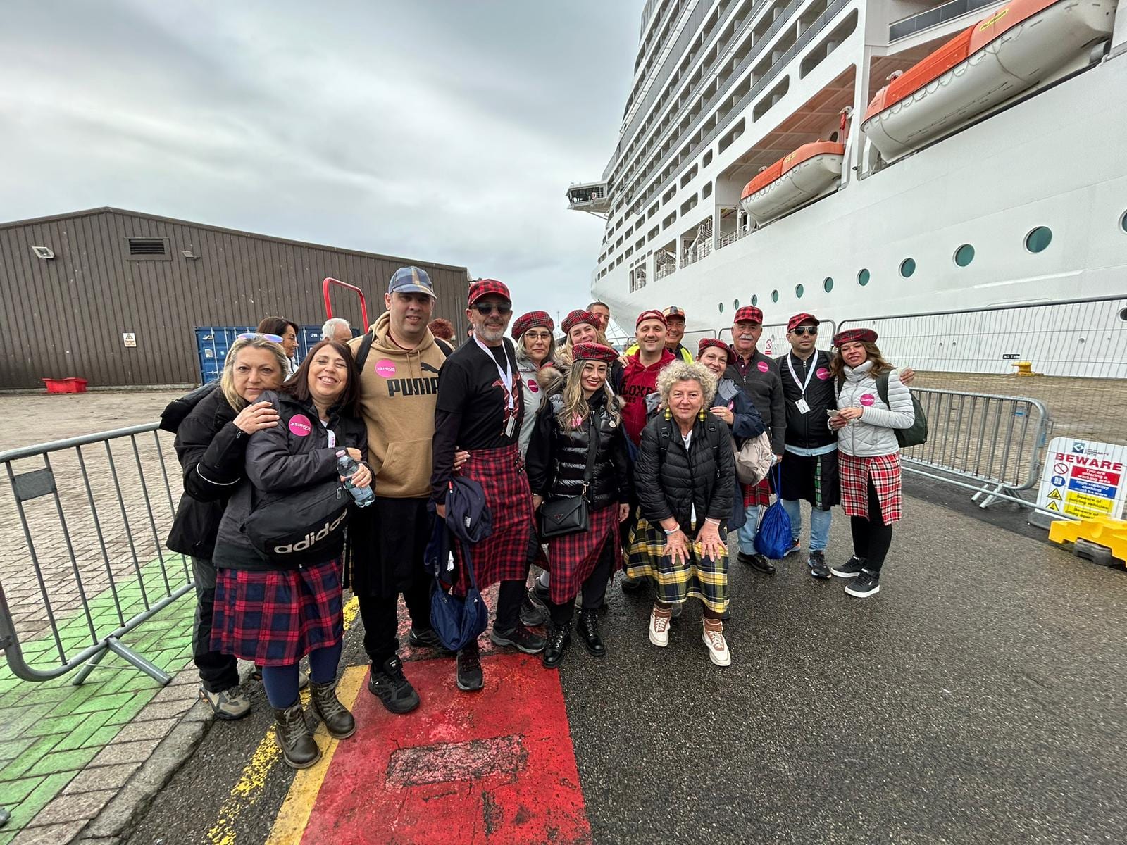 El grupo, con boinas y faldas escocesas, junto al barco en Kirkwall